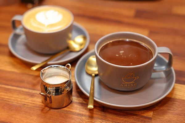 Arise coffees on a table next to a small milk jug