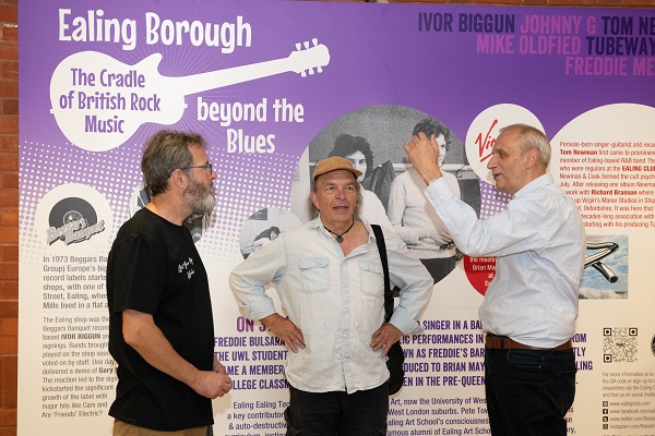 Three people standing next to an exhibition panel