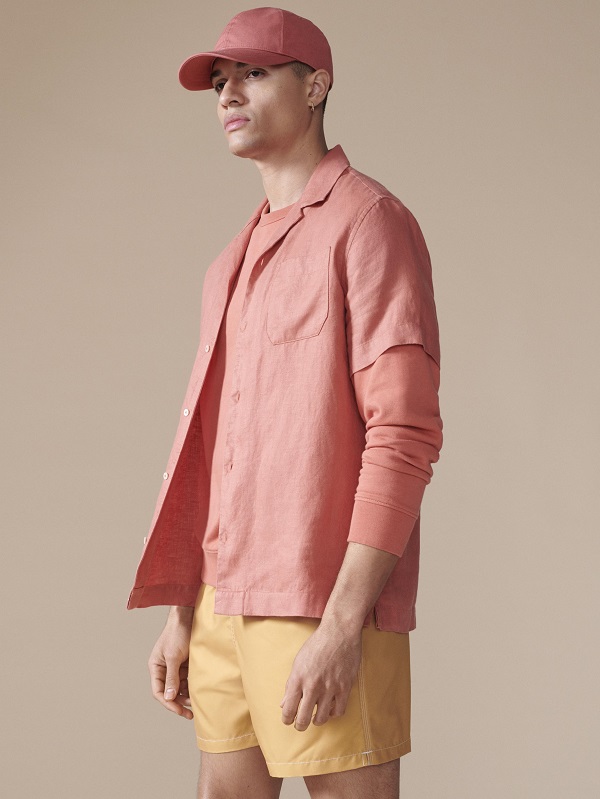 A model wearing all peach clothing including a shirt, shorts and a baseball cap