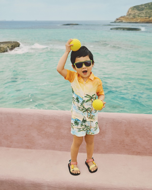 A child wearing sandals and colourful hawaiian print clothing